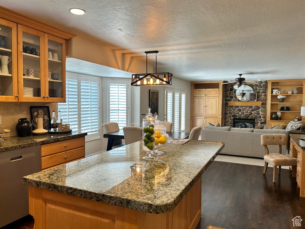 Kitchen with stainless steel dishwasher, a textured ceiling, dark wood-style floors, open floor plan, and glass insert cabinets