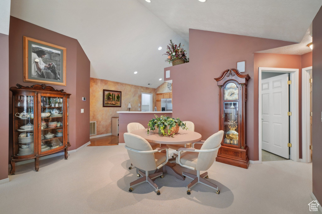 Carpeted dining room with lofted ceiling, baseboards, and recessed lighting