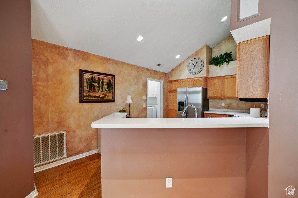 Kitchen featuring stainless steel fridge with ice dispenser, wood finished floors, baseboards, lofted ceiling, and light countertops