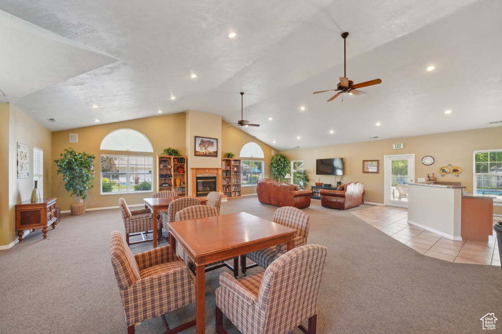 Dining area featuring light colored carpet, ceiling fan, lofted ceiling, recessed lighting, and a glass covered fireplace