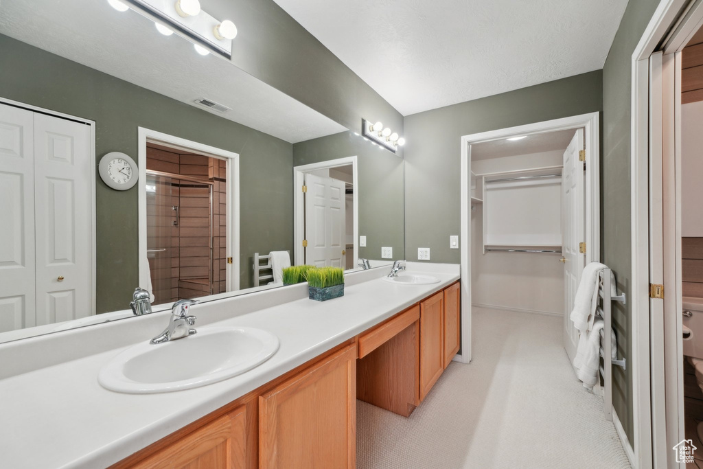 Bathroom with a closet, double vanity, a shower, and baseboards