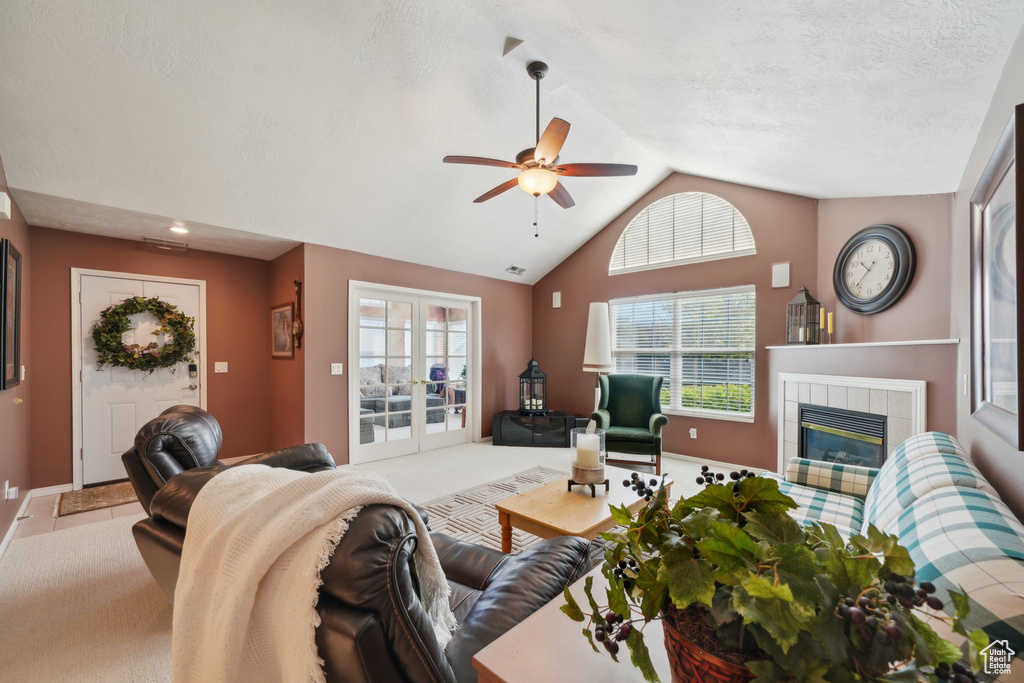 Living room with a tile fireplace, lofted ceiling, a ceiling fan, french doors, and baseboards