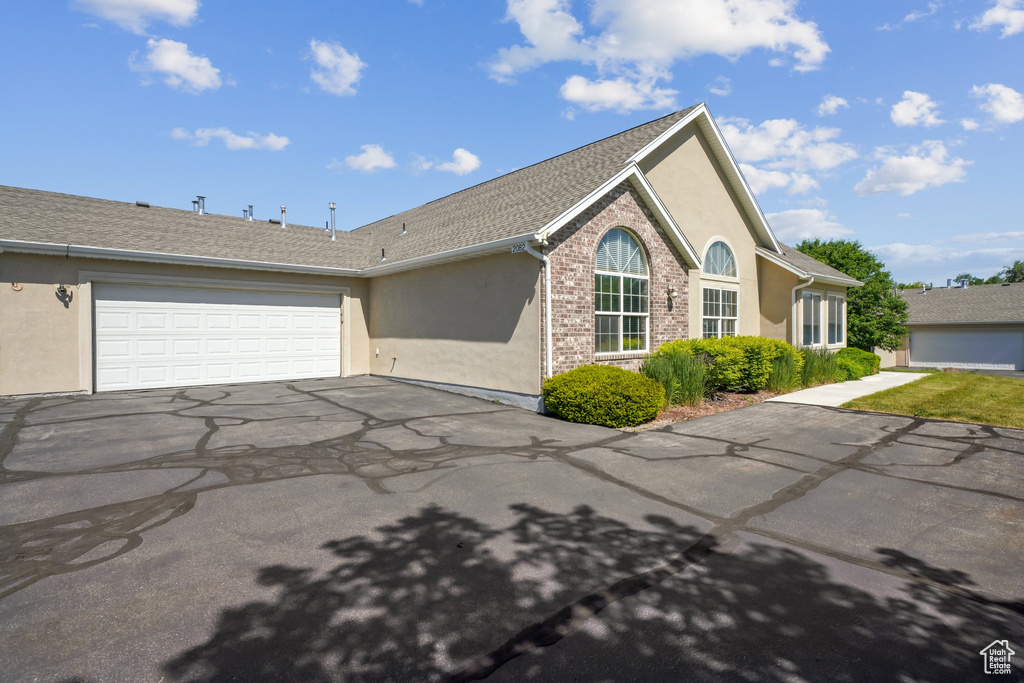 View of front of house featuring asphalt driveway, stucco siding, a garage, and a shingled roof