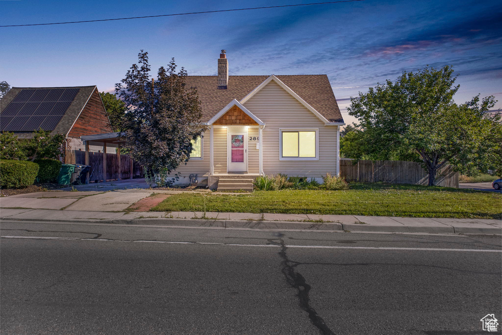 View of front facade with a chimney, roof with shingles, and driveway
