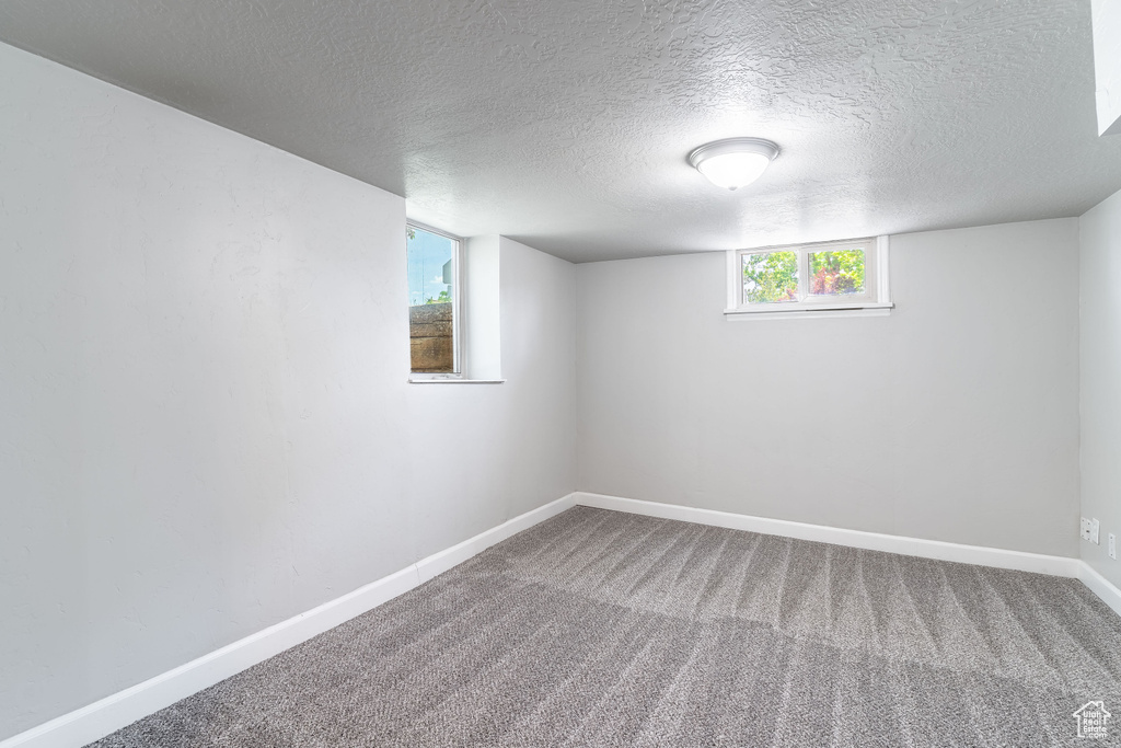 Basement featuring baseboards, carpet, and a textured ceiling