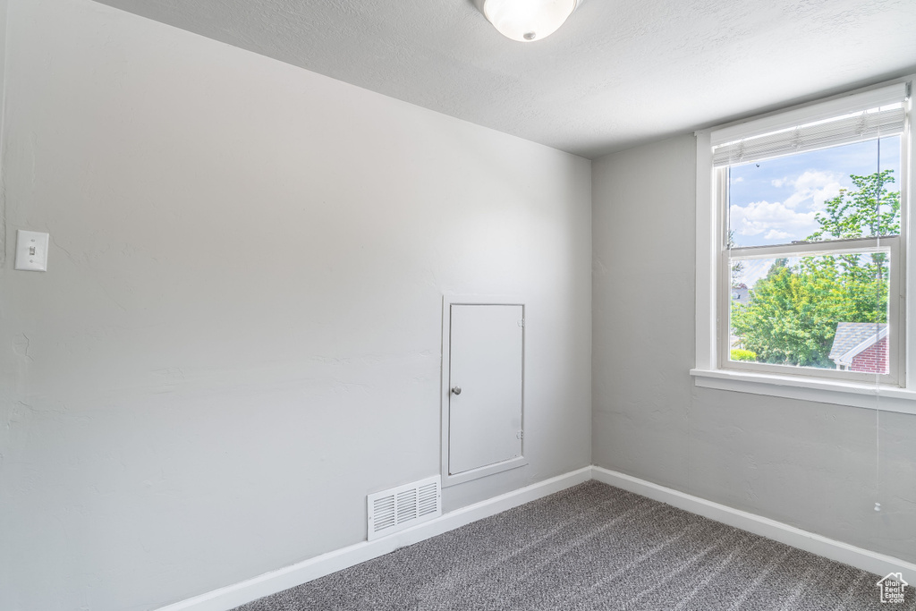 Unfurnished room with dark colored carpet and baseboards
