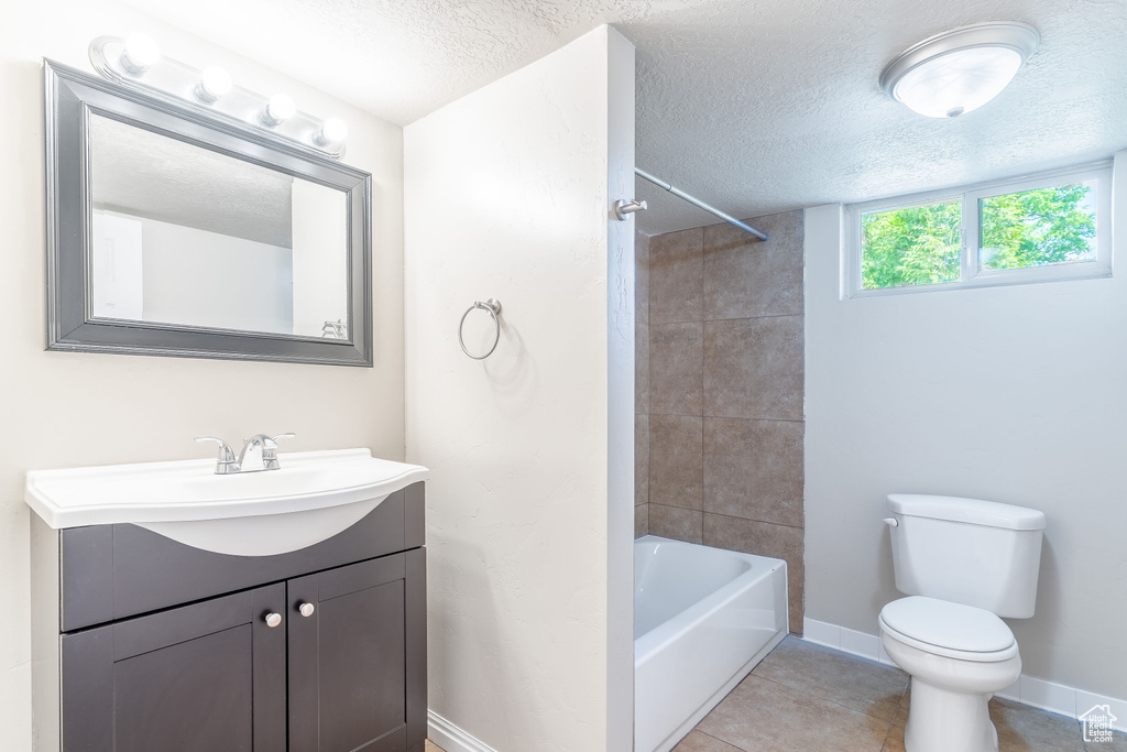 Bathroom featuring toilet, a textured ceiling, vanity, shower / bathtub combination, and tile patterned floors