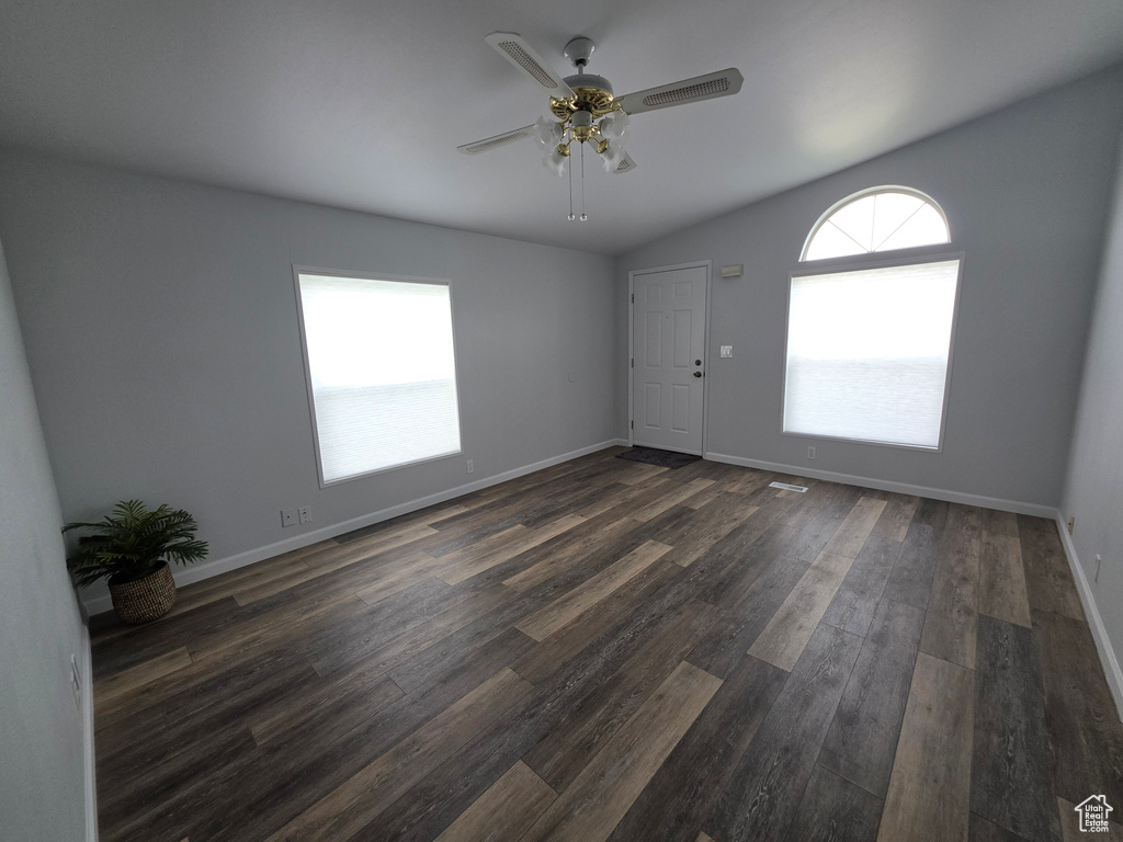 Unfurnished room with lofted ceiling, a ceiling fan, dark wood-style flooring, and baseboards