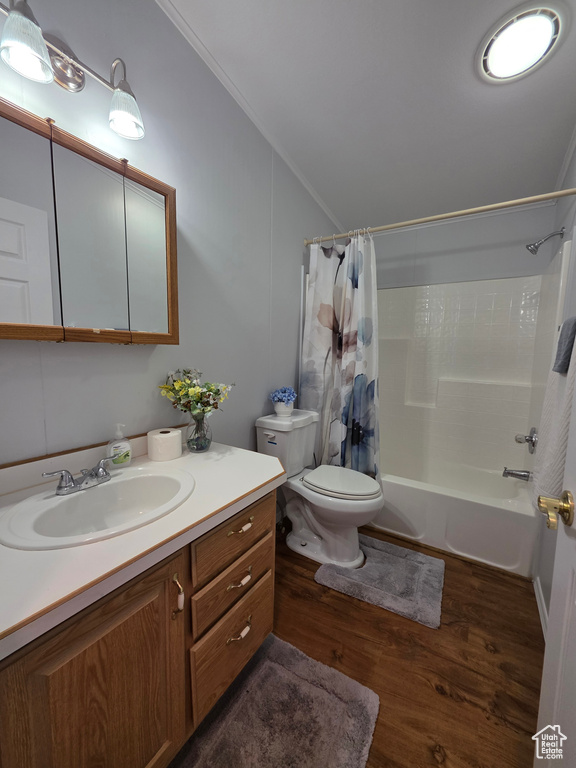 Bathroom with shower / bath combination with curtain, wood finished floors, vanity, toilet, and vaulted ceiling