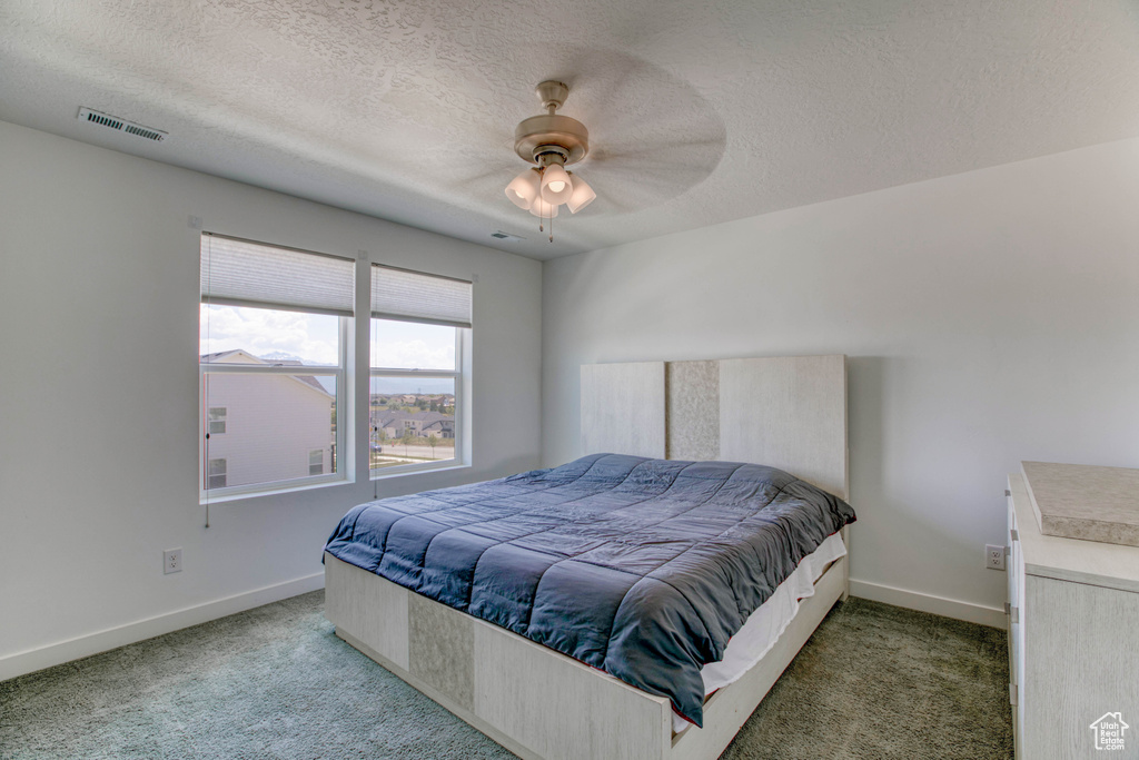 Bedroom with carpet floors, baseboards, a textured ceiling, and a ceiling fan