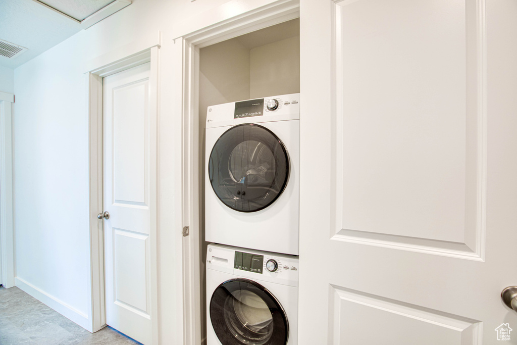 Laundry room with stacked washer and clothes dryer and baseboards