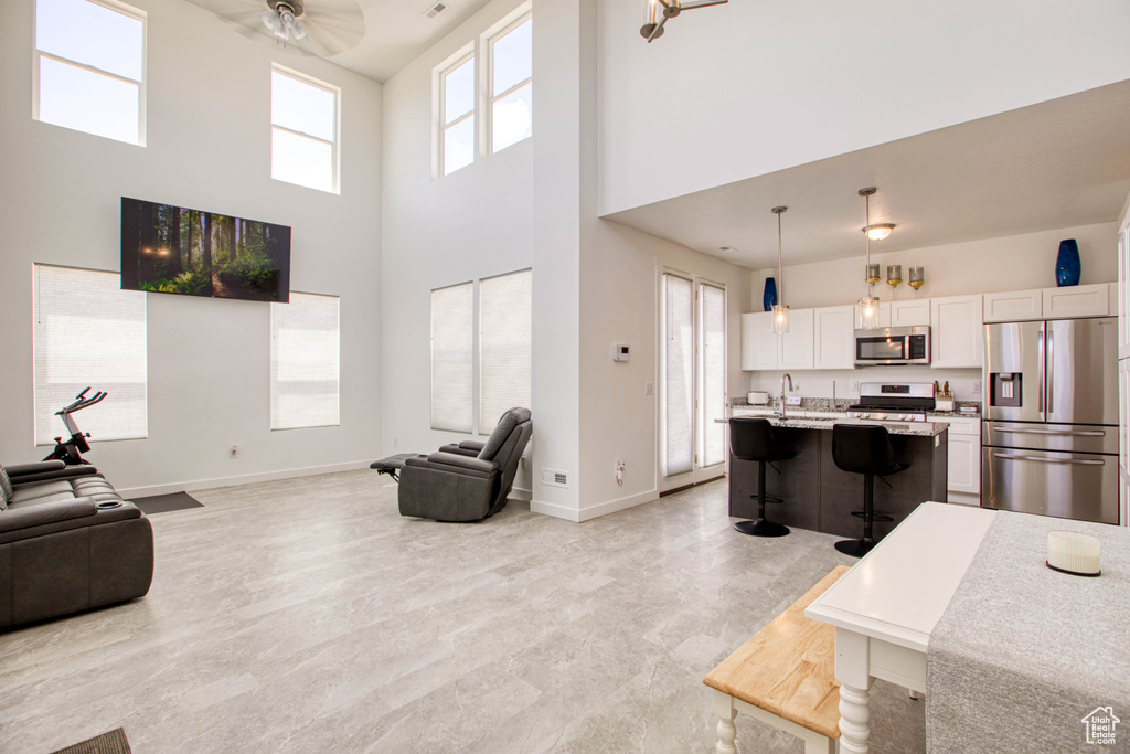 Living area featuring baseboards, a towering ceiling, and ceiling fan