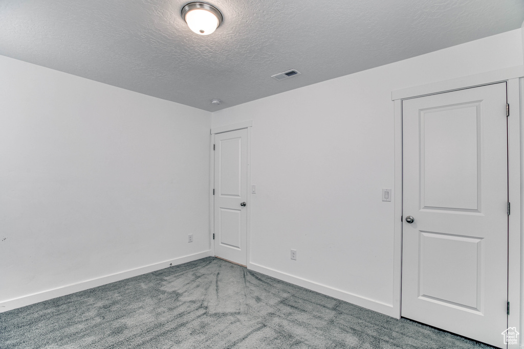 Unfurnished bedroom featuring a textured ceiling, carpet floors, and baseboards