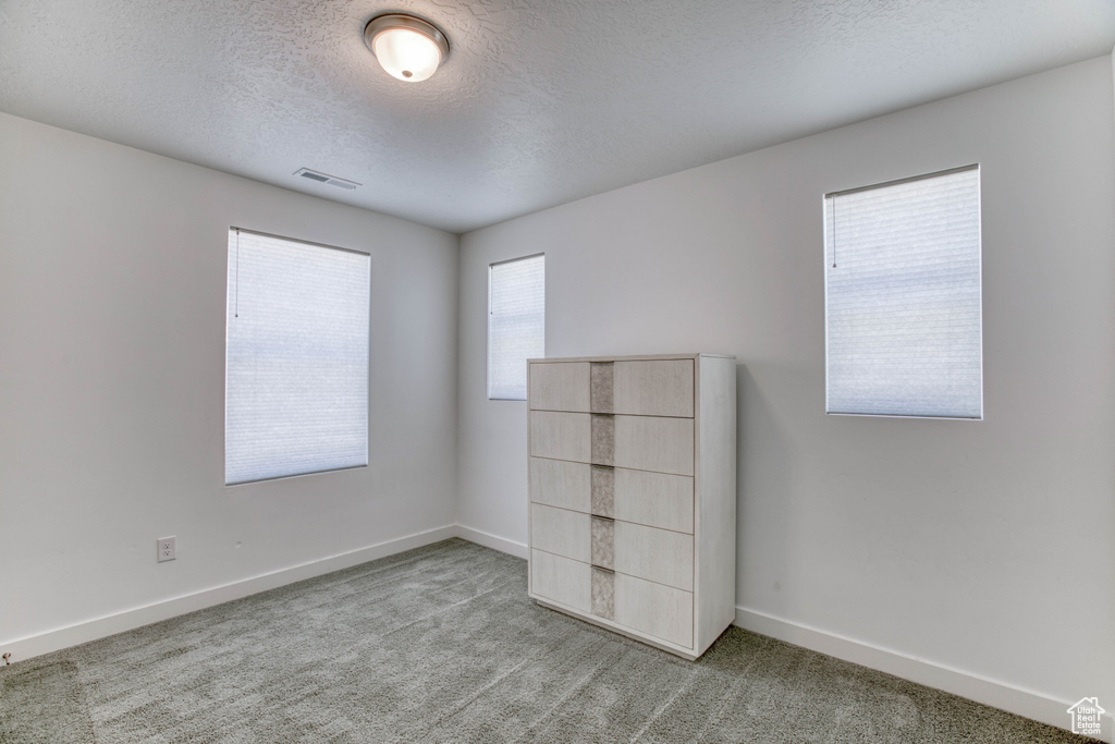 Unfurnished bedroom featuring a textured ceiling, carpet floors, and baseboards