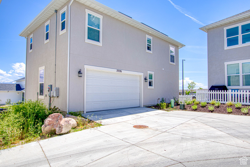 View of property exterior featuring a garage, concrete driveway, and stucco siding