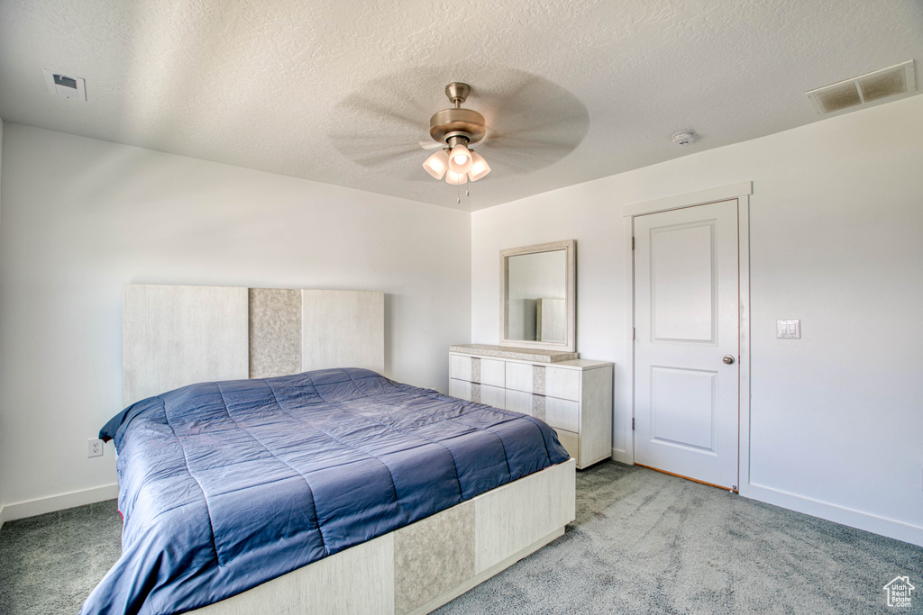 Bedroom featuring light colored carpet, baseboards, a textured ceiling, and a ceiling fan
