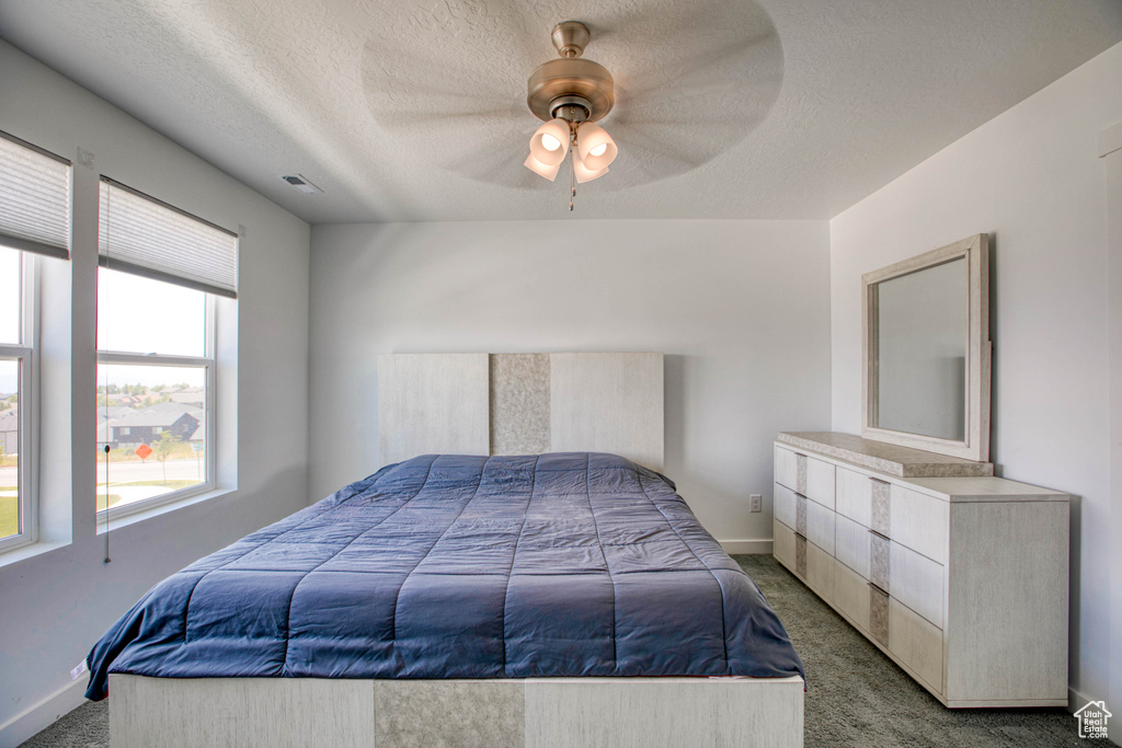 Bedroom with carpet, a textured ceiling, baseboards, and ceiling fan