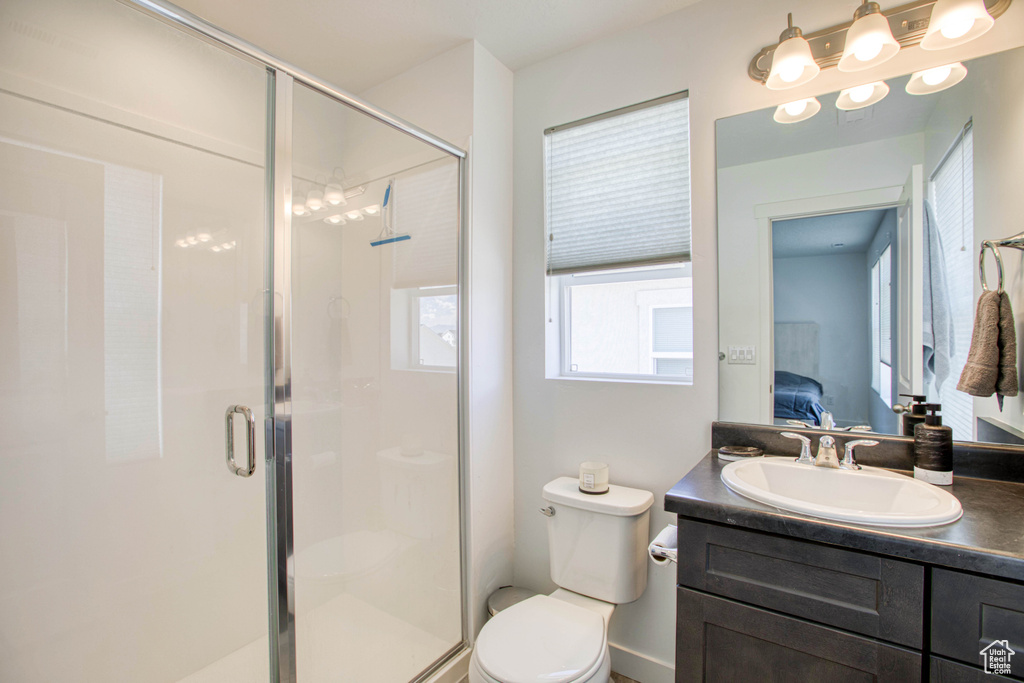 Ensuite bathroom with toilet, vanity, a shower stall, and baseboards