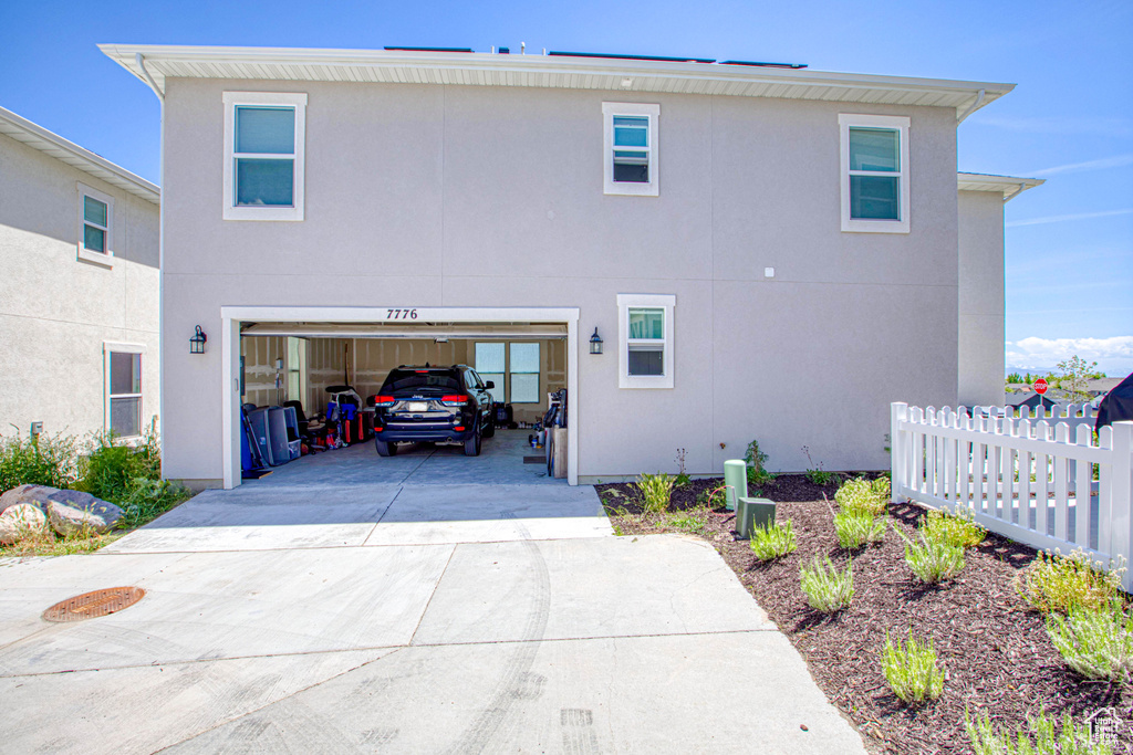 View of side of property featuring driveway, stucco siding, and a garage