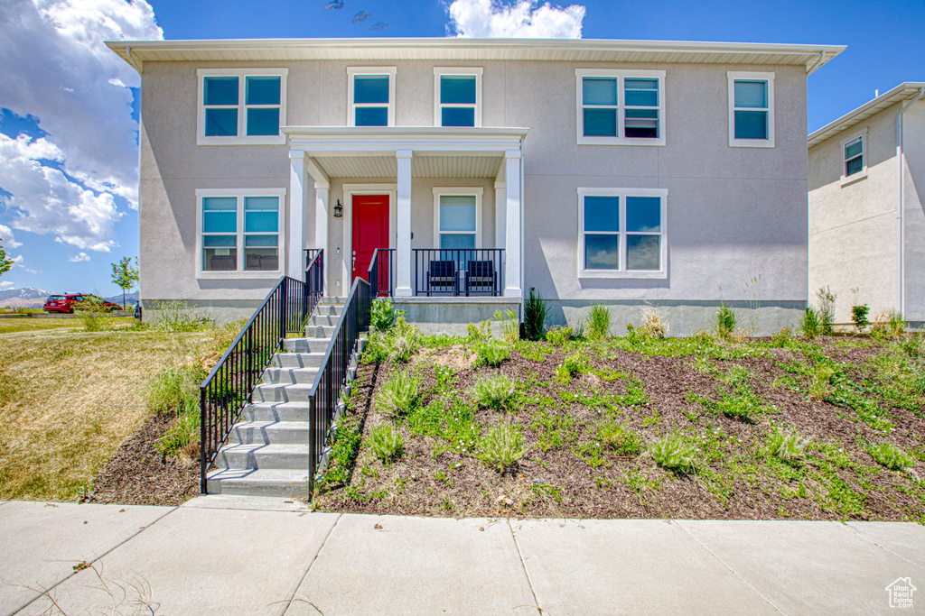View of front of property with a porch, stucco siding, and stairs