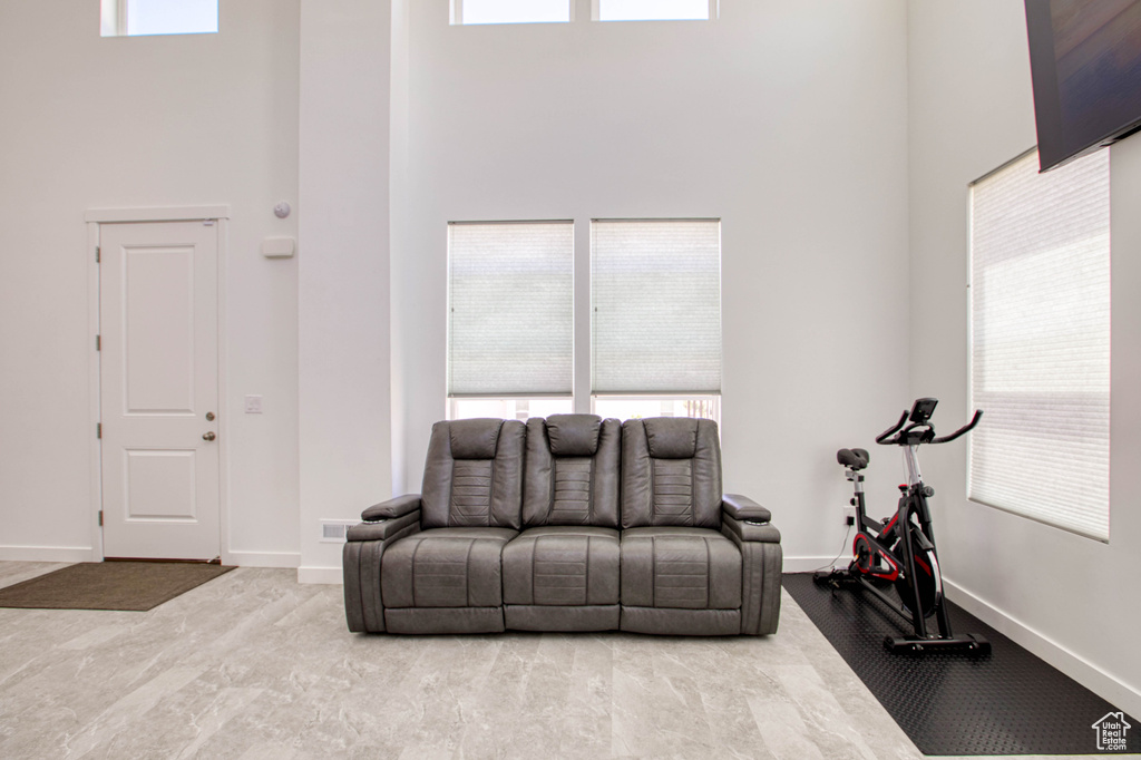 Living area featuring a high ceiling, baseboards, and healthy amount of natural light