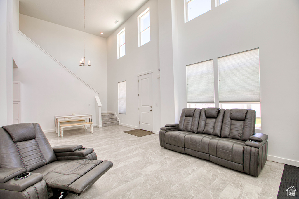 Living area featuring a high ceiling, a chandelier, stairway, baseboards, and carpet flooring
