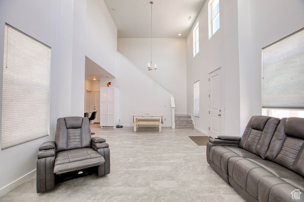 Living area with a towering ceiling, baseboards, a chandelier, and stairs