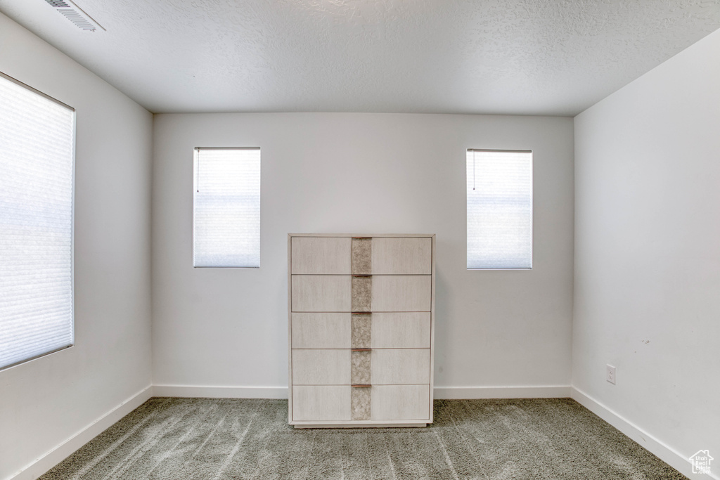Unfurnished bedroom featuring carpet, baseboards, and a textured ceiling