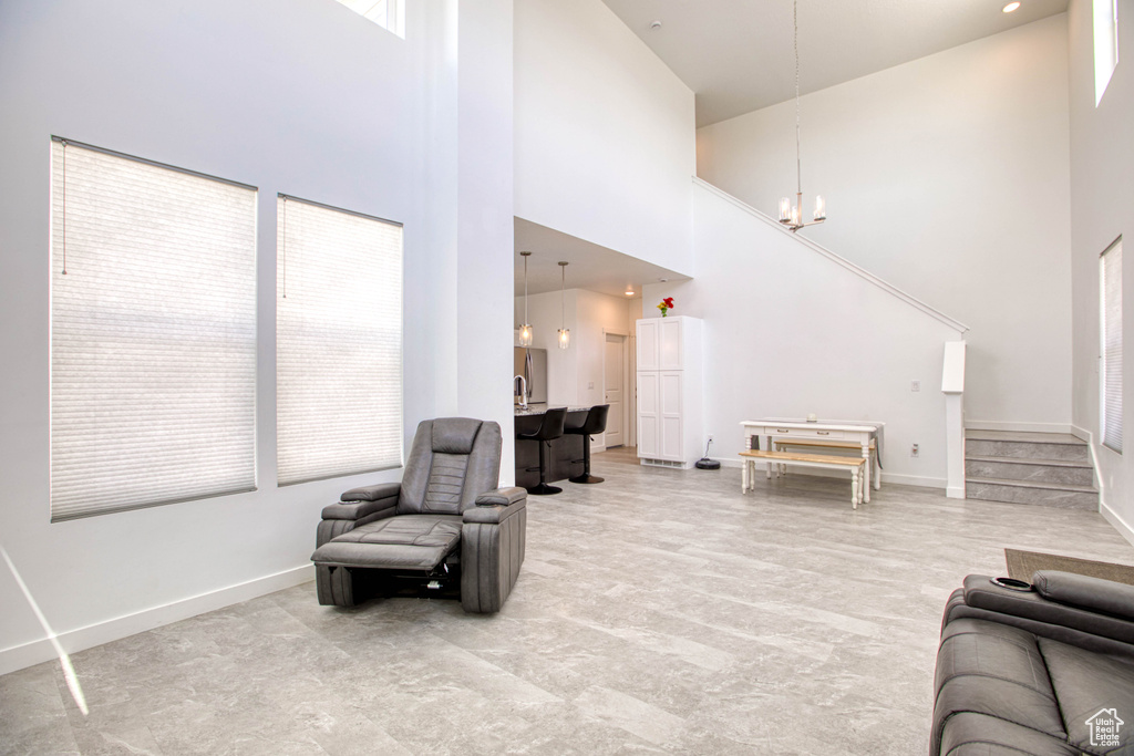 Living area featuring a towering ceiling, a chandelier, and baseboards
