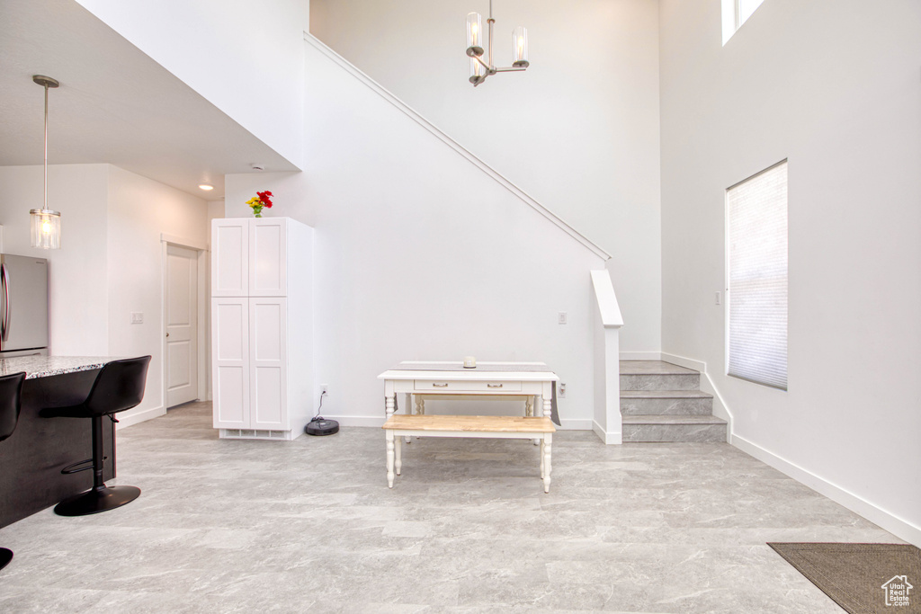 Living room featuring a towering ceiling, stairway, baseboards, healthy amount of natural light, and a chandelier