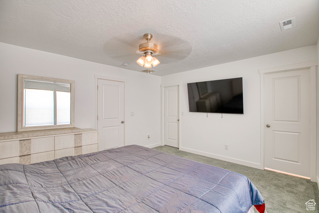 Carpeted bedroom with a textured ceiling, baseboards, and a ceiling fan