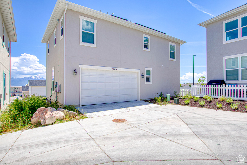 View of side of property featuring a garage, concrete driveway, stucco siding, and a mountain view