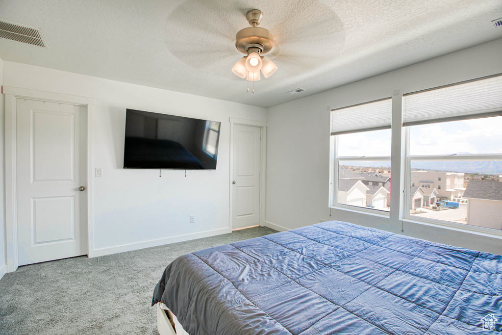 Carpeted bedroom featuring baseboards, a textured ceiling, and ceiling fan