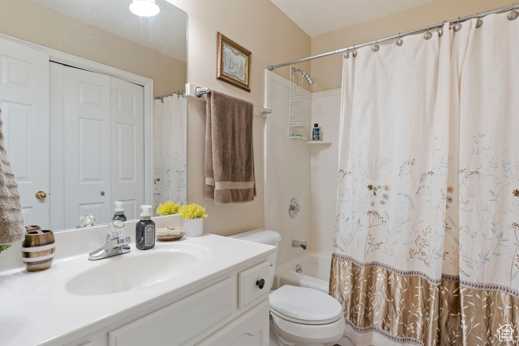 Bathroom featuring vanity, shower / bath combination with curtain, and toilet