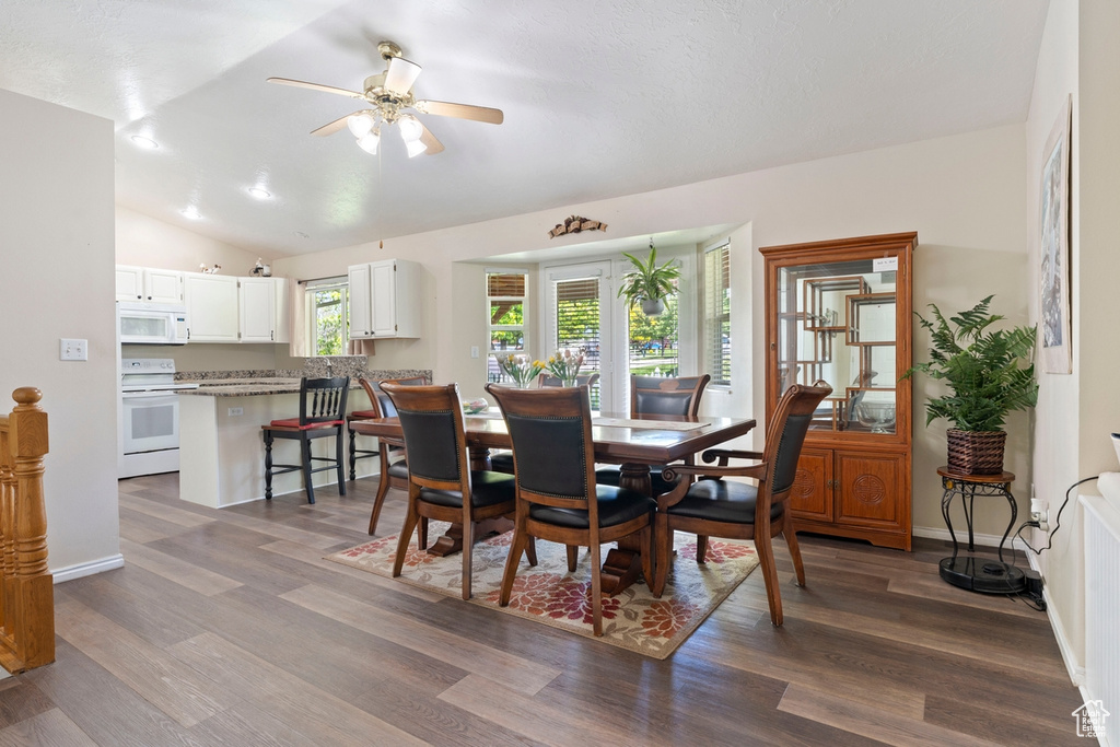 Dining area featuring ceiling fan, dark wood-type flooring, vaulted ceiling, and baseboards