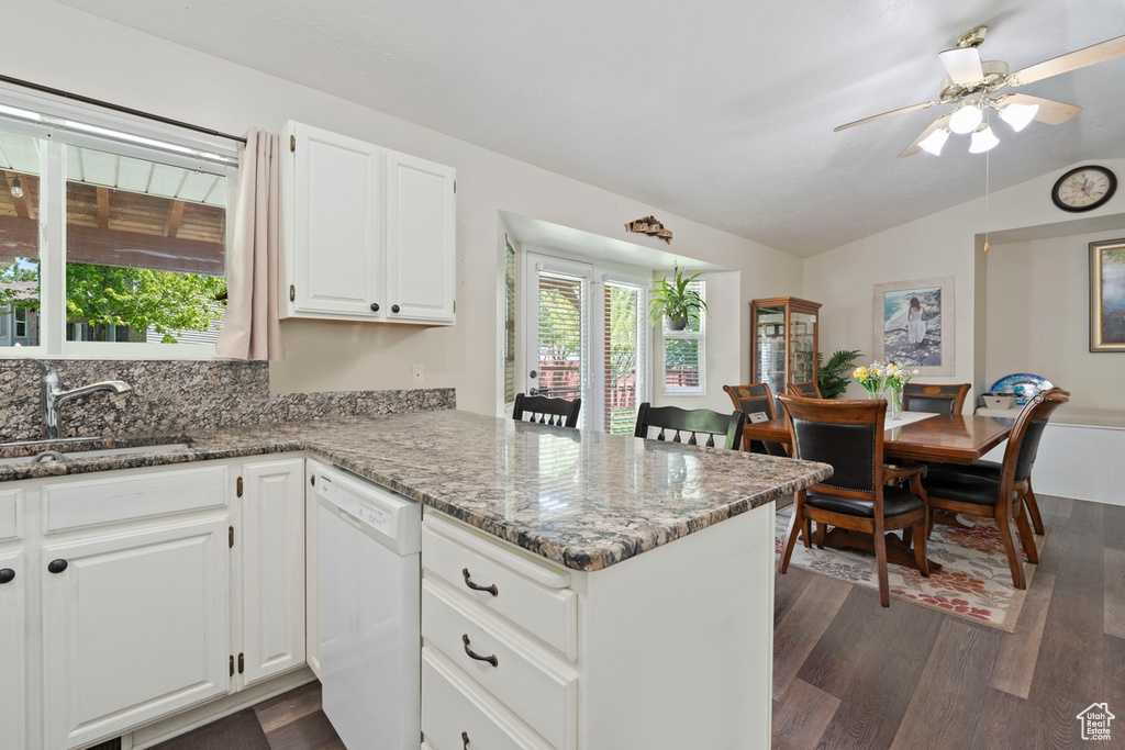Kitchen with dishwasher, a sink, vaulted ceiling, a peninsula, and dark wood finished floors