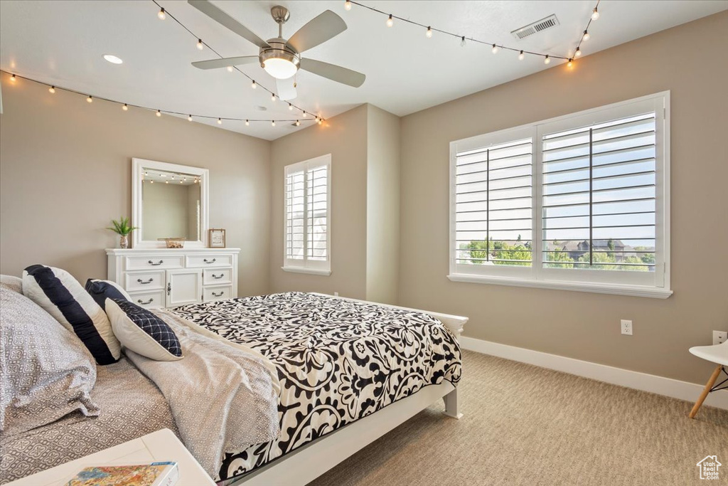 Carpeted bedroom with baseboards, multiple windows, and ceiling fan