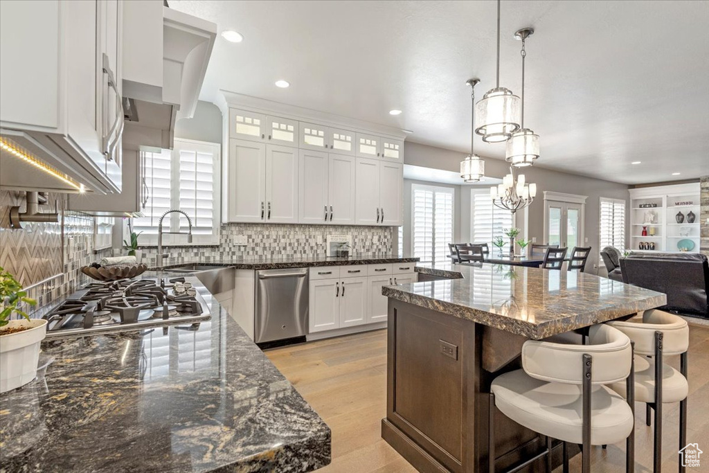 Kitchen featuring stainless steel appliances, a breakfast bar, a center island, decorative backsplash, and glass insert cabinets