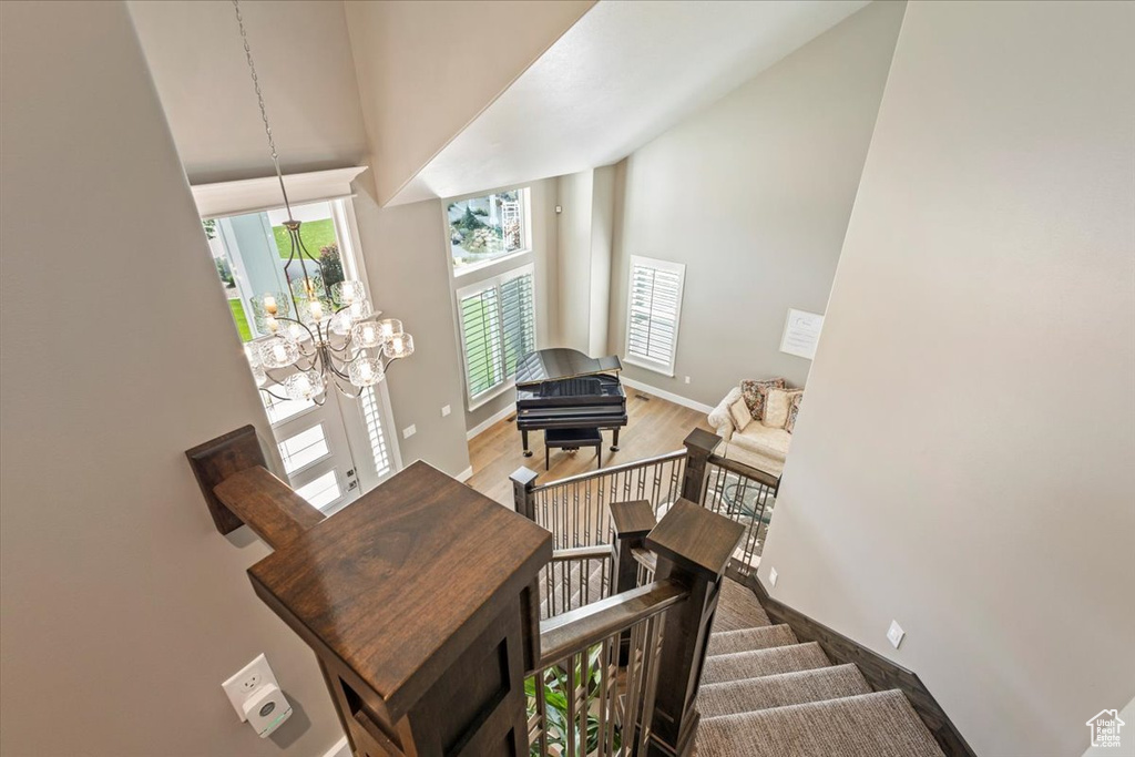 Staircase featuring high vaulted ceiling, a chandelier, baseboards, and wood finished floors