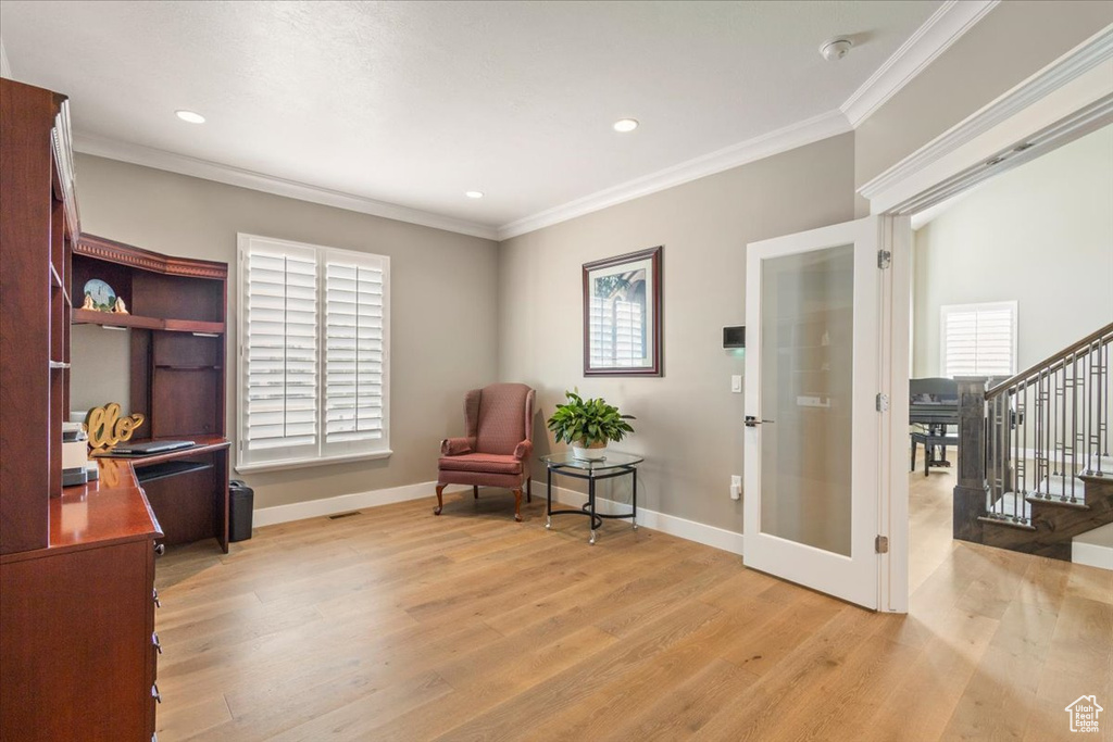 Living area featuring french doors, light wood-style floors, ornamental molding, stairs, and baseboards