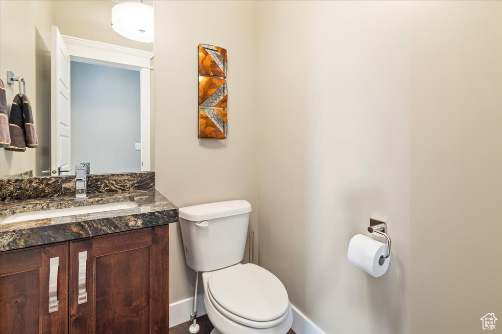 Bathroom with toilet, vanity, and baseboards
