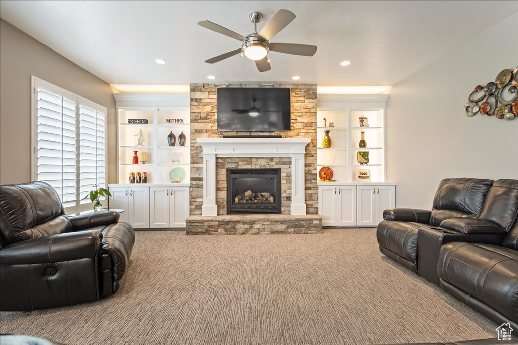 Carpeted living area featuring ceiling fan, a stone fireplace, recessed lighting, and built in features