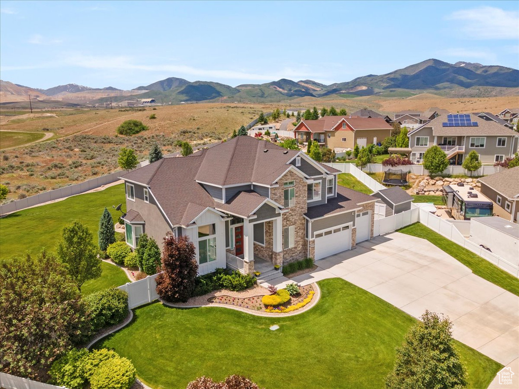 View of front of property with driveway, stone siding, a residential view, and a mountain view