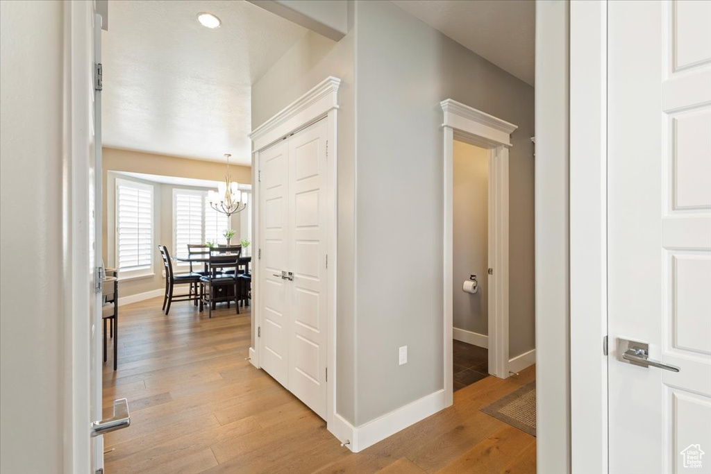 Hall with a chandelier, baseboards, and light wood-style floors