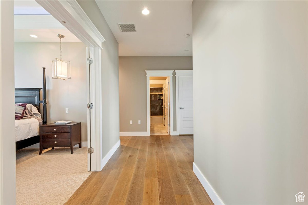 Hallway with light wood-style flooring, baseboards, recessed lighting, and a chandelier