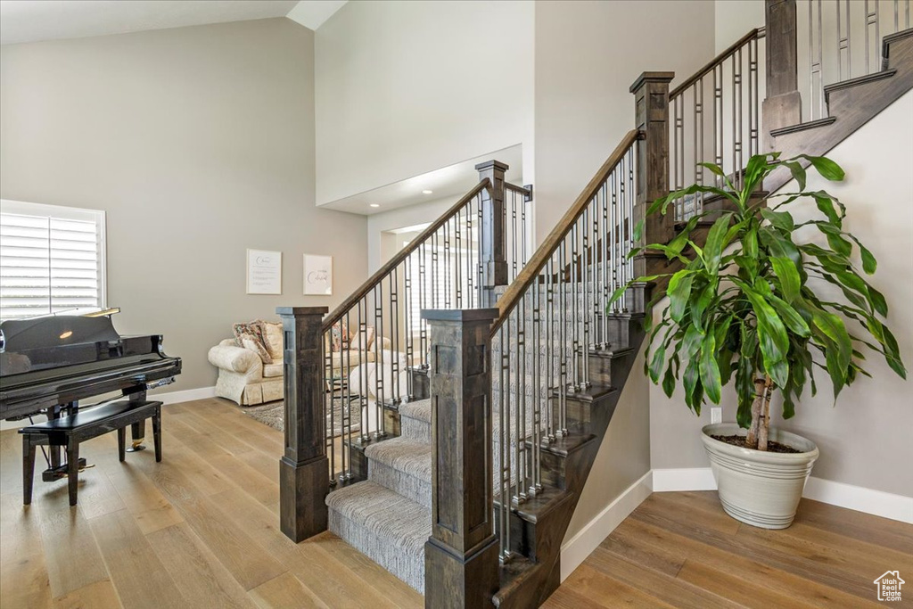 Stairway featuring high vaulted ceiling, baseboards, and wood finished floors