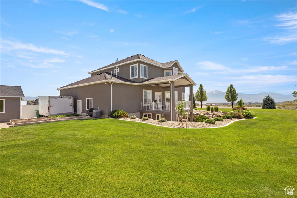 Rear view of property with a yard, stucco siding, cooling unit, and a mountain view
