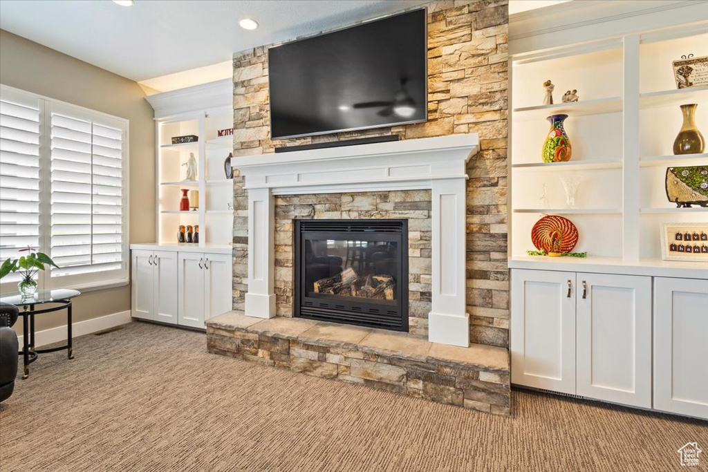 Living area featuring a stone fireplace, baseboards, carpet, recessed lighting, and built in features