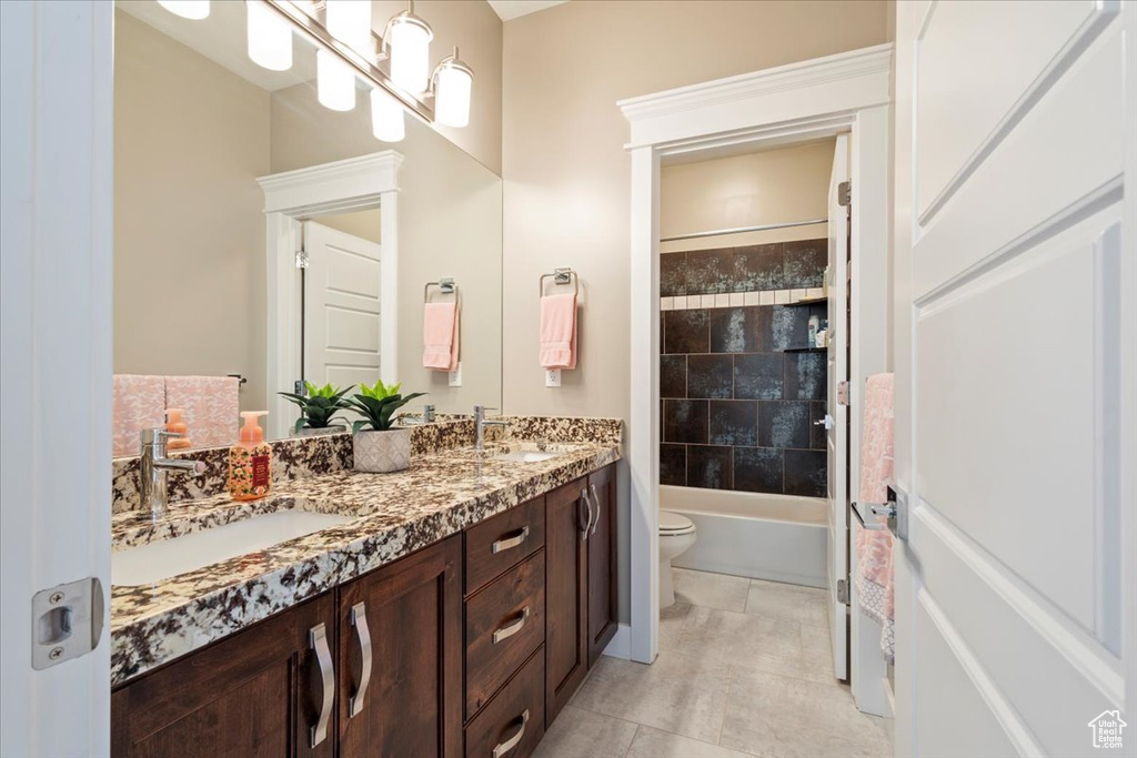 Bathroom featuring double vanity, toilet, shower / bathtub combination, and tile patterned flooring