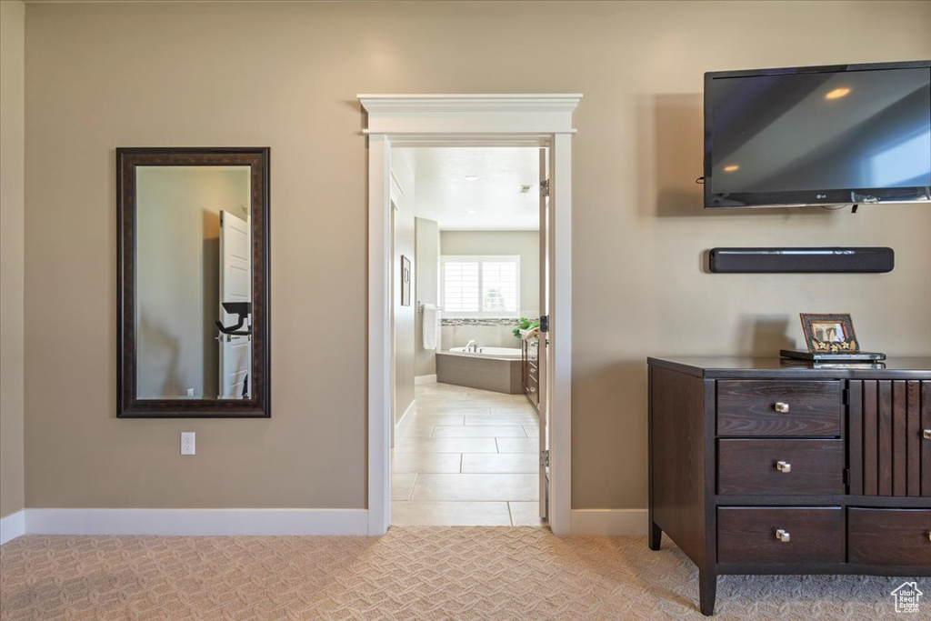 Bedroom with baseboards, connected bathroom, light tile patterned floors, and light carpet